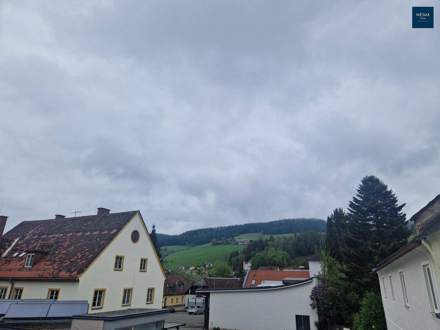 Weitläufiger Blick auf grüne Hügel und die umliegende Landschaft unter bewölktem Himmel.