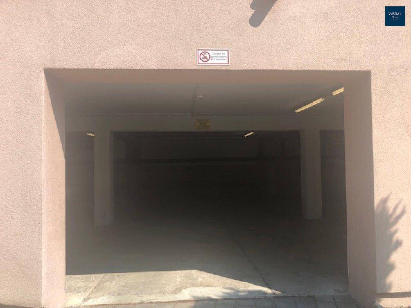 Breiter Eingang zur Tiefgarage mit Beleuchtung und Hinweisschildern.