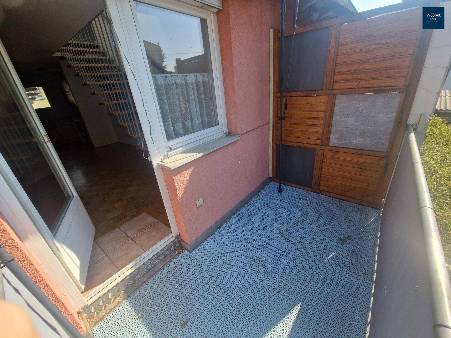 Balkon mit Sichtschutz und Zugang zum Innenbereich, mit Blick ins Grüne.