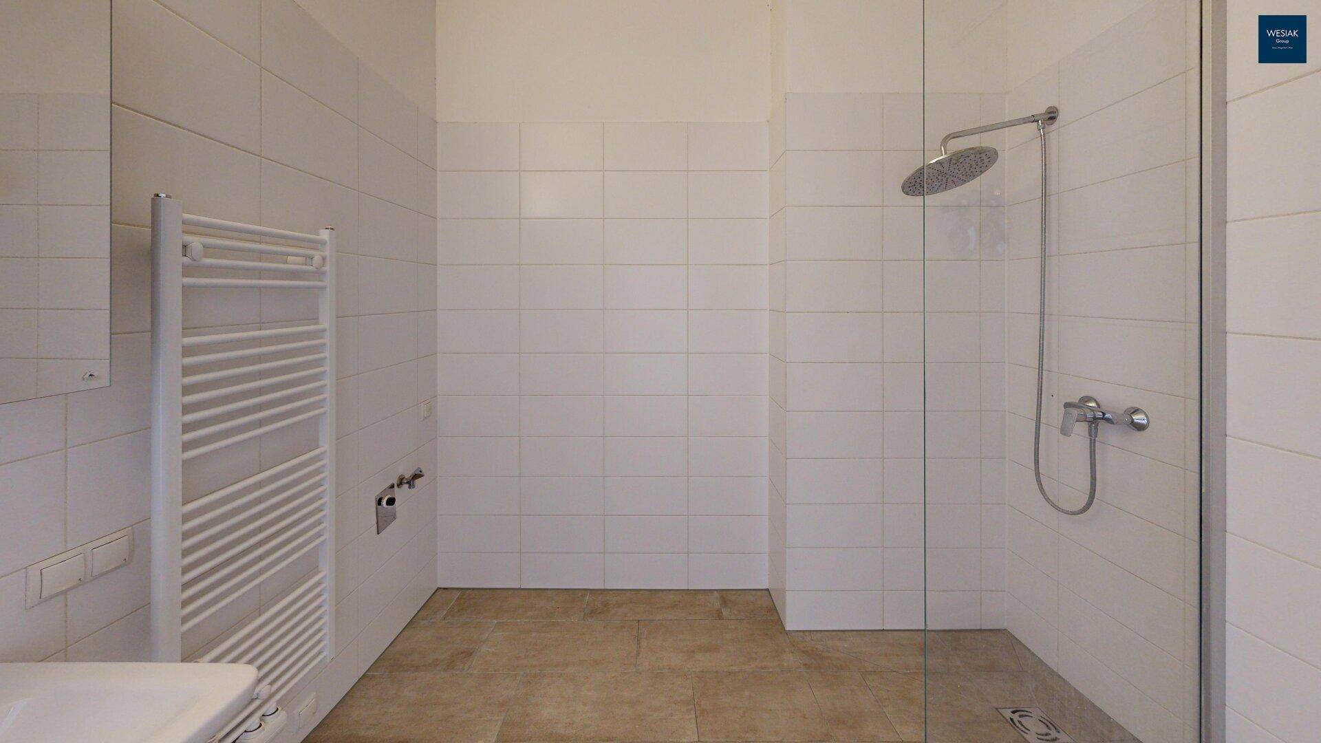 Geräumiges Badezimmer mit moderner begehbarer Dusche und weißen Wandfliesen.