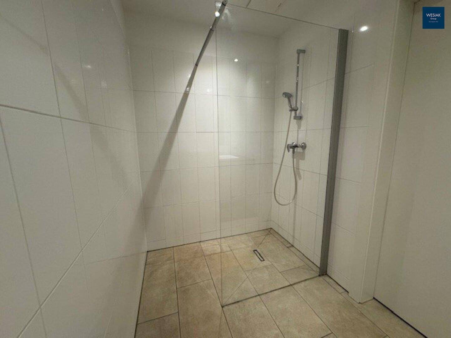 Moderne Duschkabine mit Glasabtrennung und weißen Fliesen im Badezimmer.