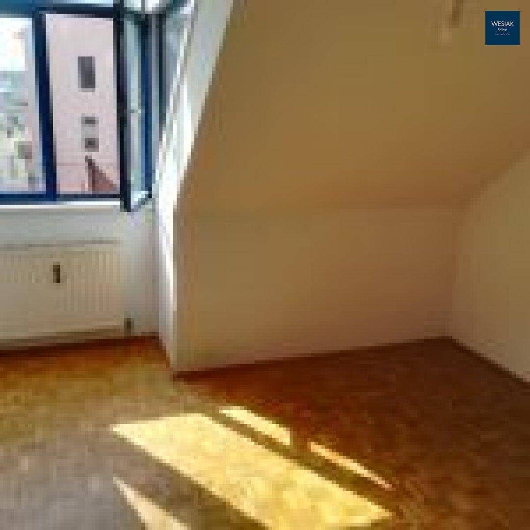 Lichtdurchfluteter Dachgeschossraum mit Parkettboden und schrägen Wänden, ideal für individuelle Gestaltung.