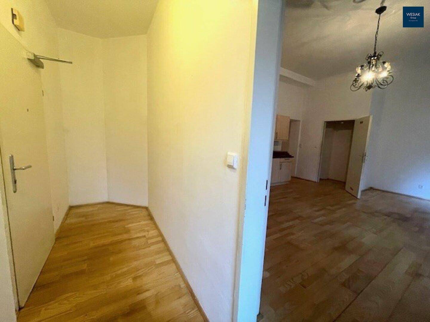 Eingangsbereich mit Parkettboden und Zugang zu den Wohnräumen, hell und einladend.