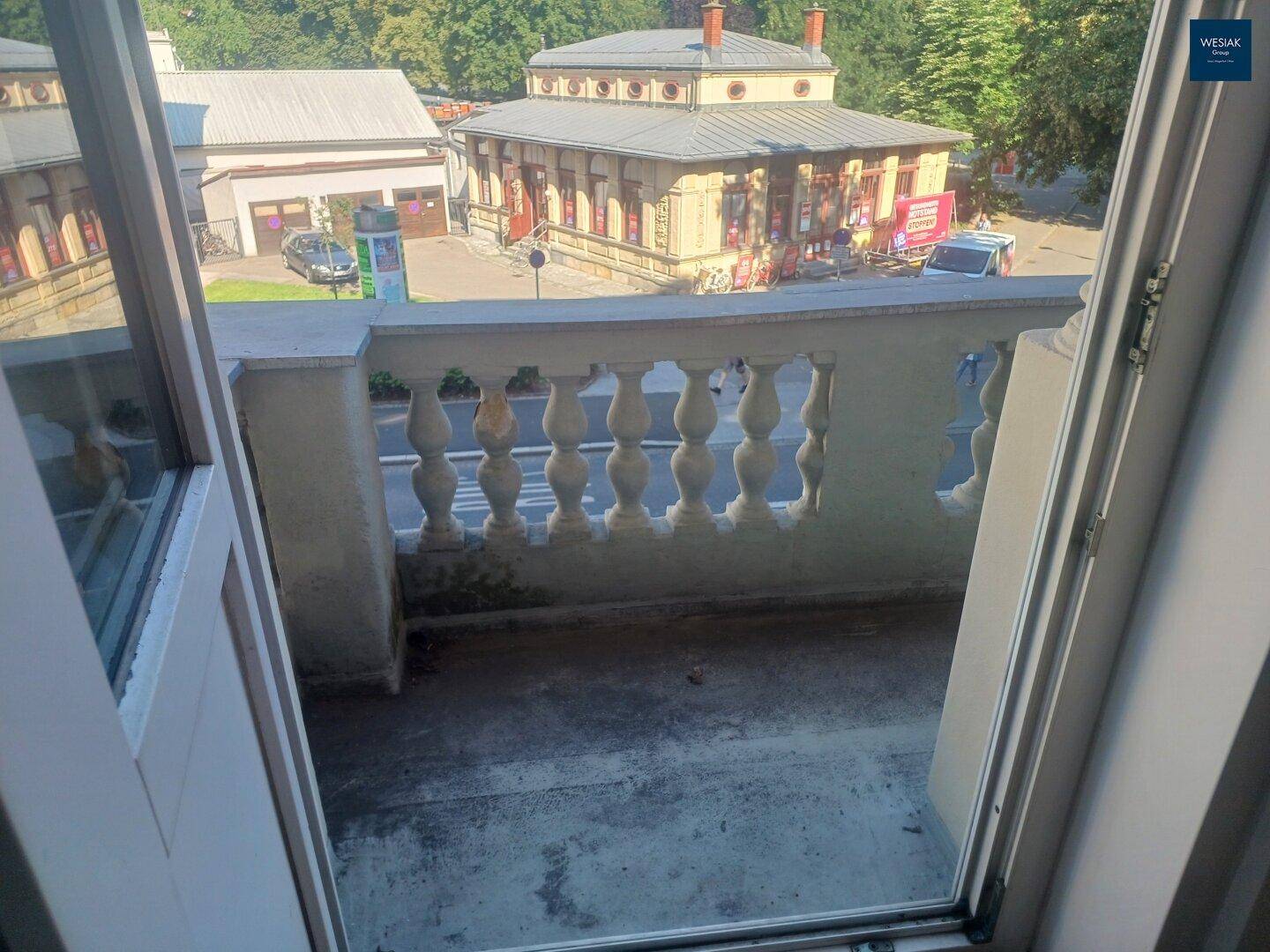 Balkon mit klassischer Balustrade und Blick auf ein historisches Gebäude gegenüber der Straße.