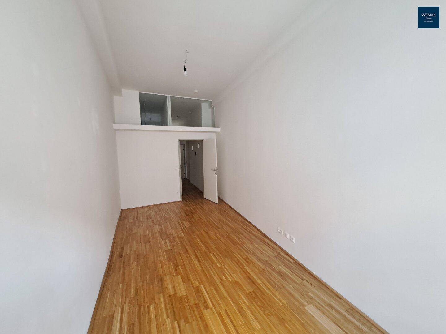 Heller und geräumiger Wohnraum mit hohen Decken und elegantem Holzparkettboden.