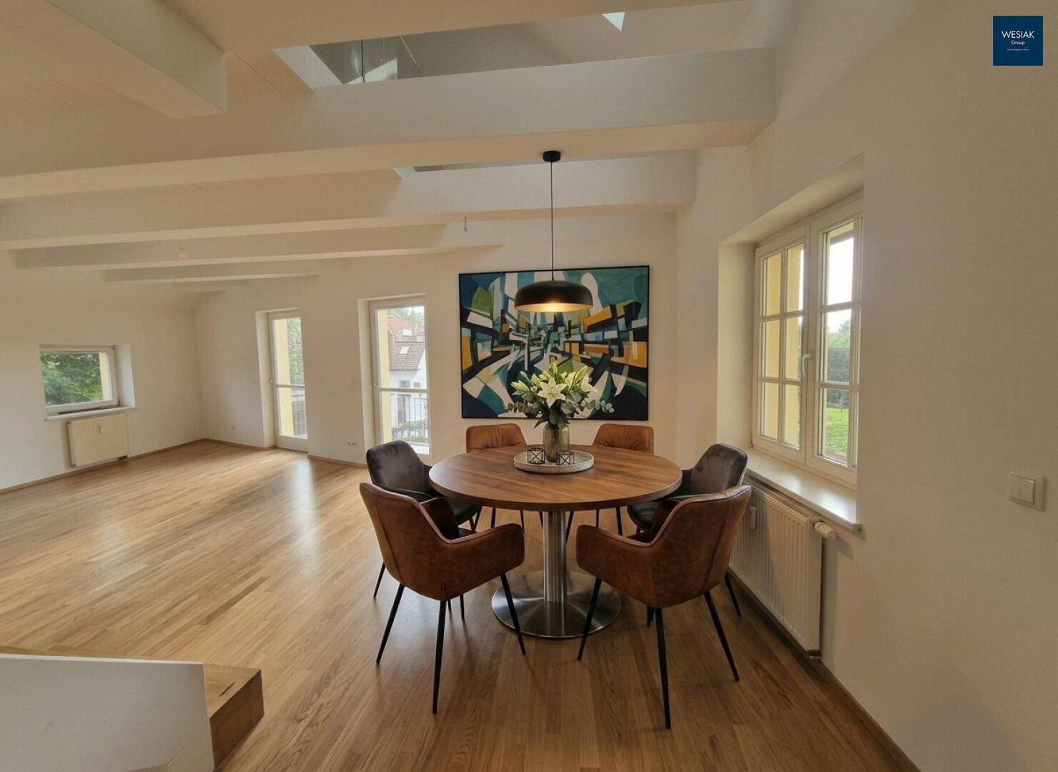 Eleganter Essbereich mit Holztisch und modernen Stühlen, großen Fenstern und viel Tageslicht.
