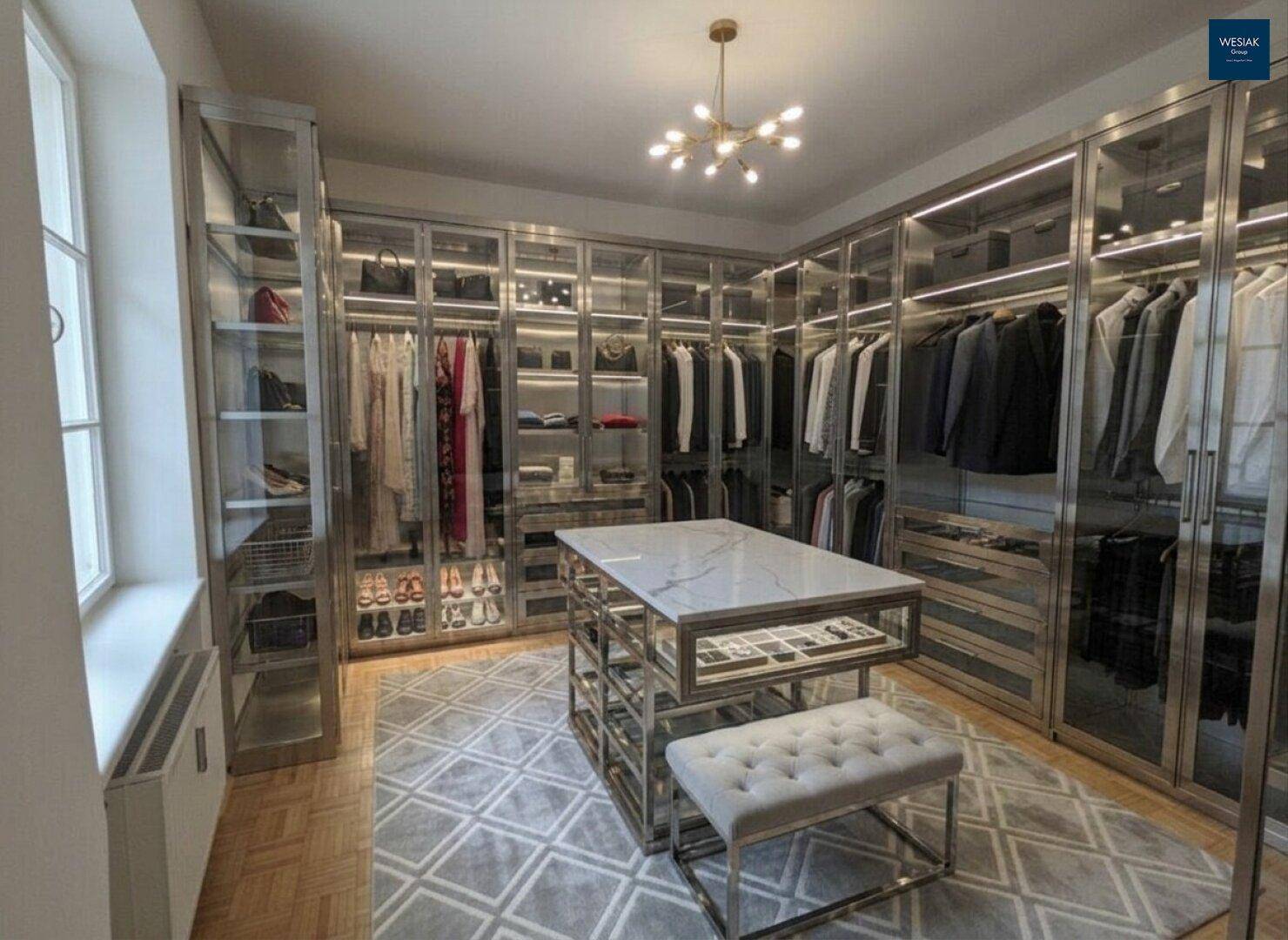 Luxuriöser begehbarer Kleiderschrank mit Glasfronten, Mittelinsel und viel Stauraum.