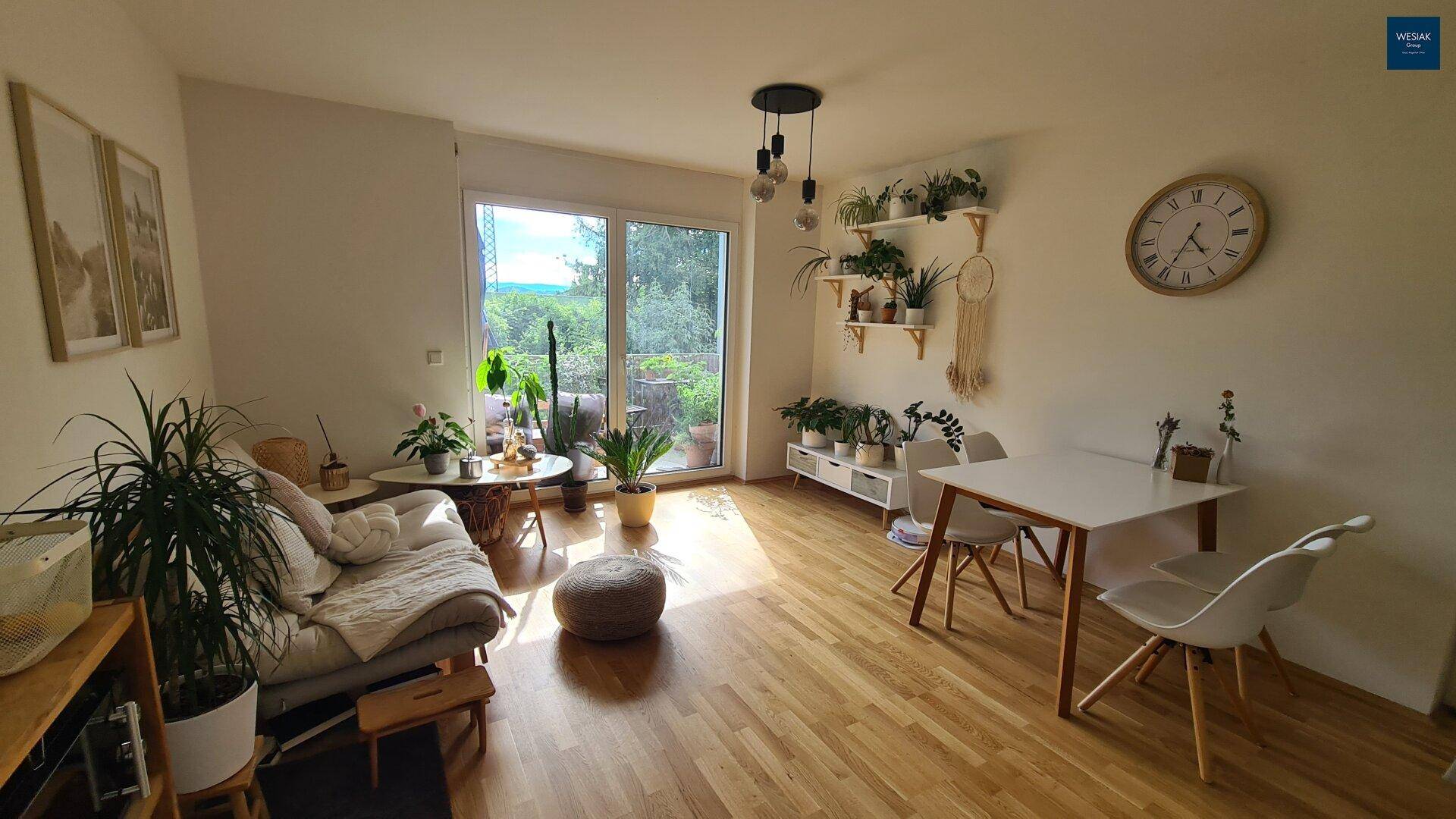 Heller Wohn- und Essbereich mit Holzboden, vielen Pflanzen und Zugang zur Terrasse.