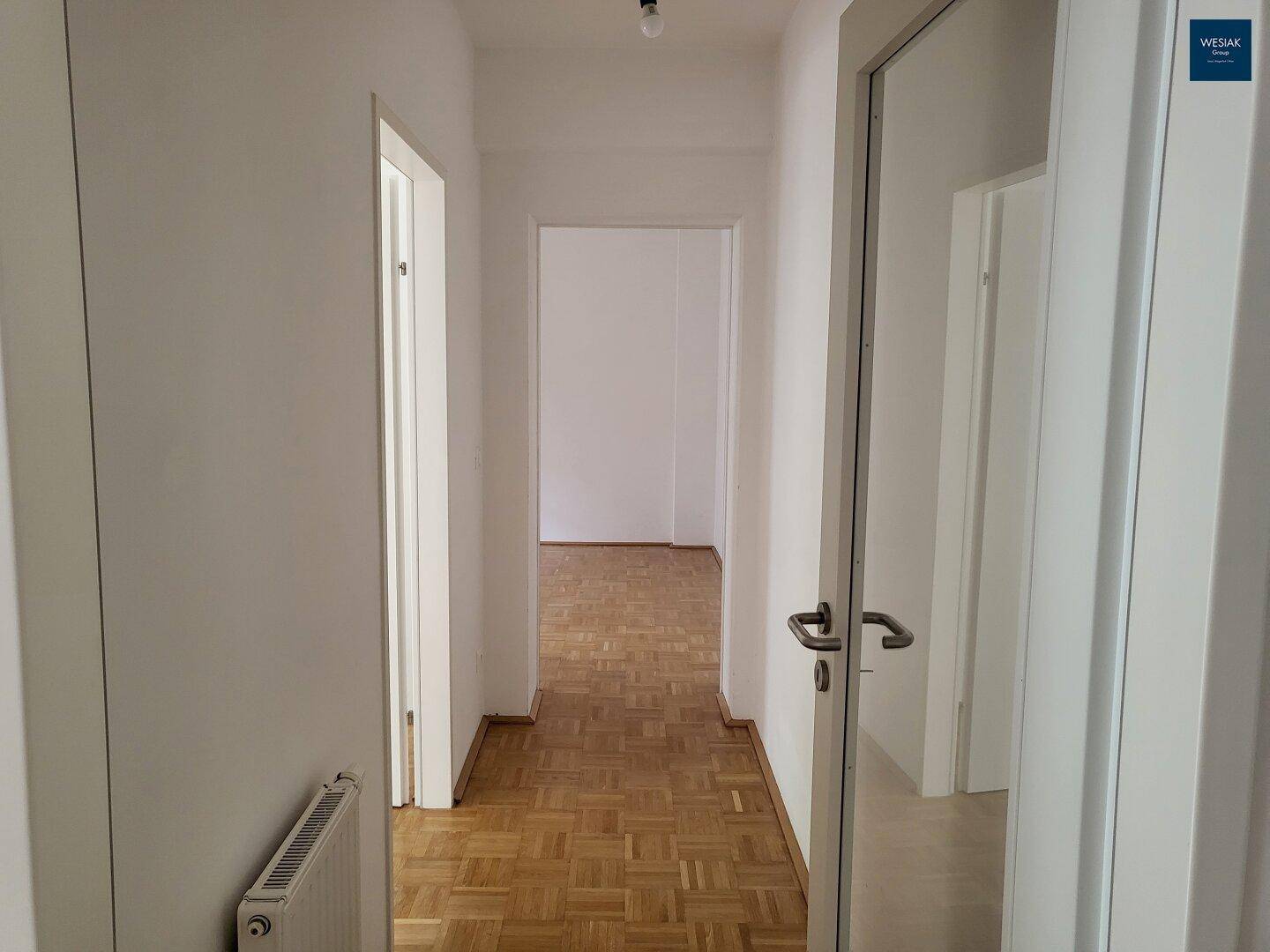 Heller Flur mit Parkettboden, der zu den verschiedenen Zimmern der Wohnung führt.