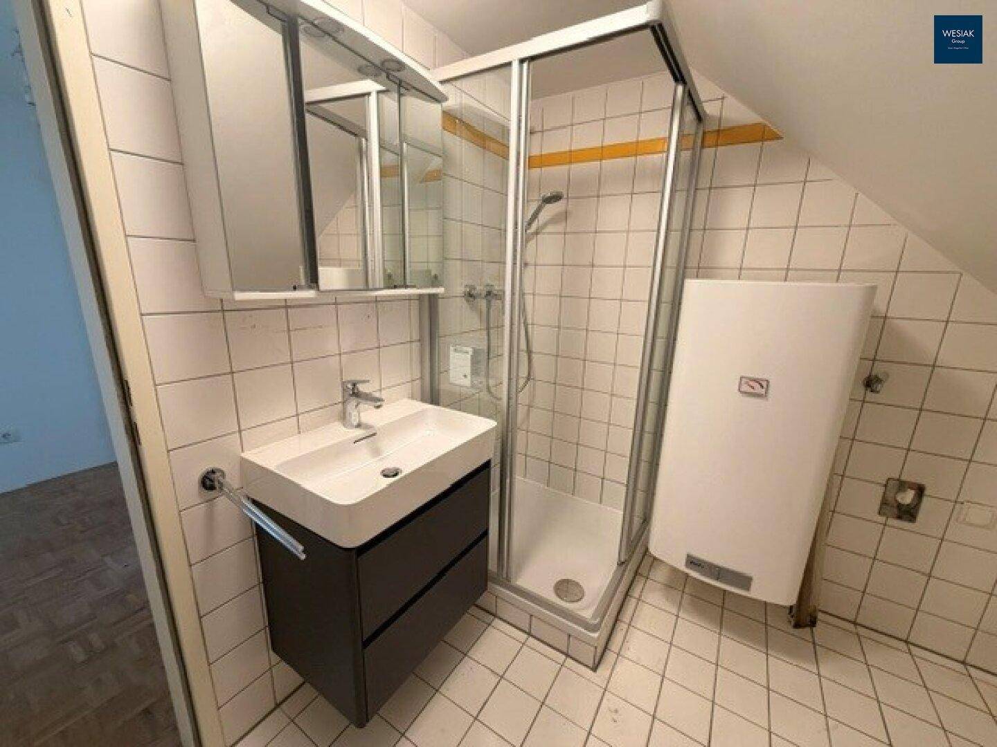 Modernes Badezimmer im Dachgeschoss mit Duschkabine, Waschbeckenunterschrank und weißen Fliesen.