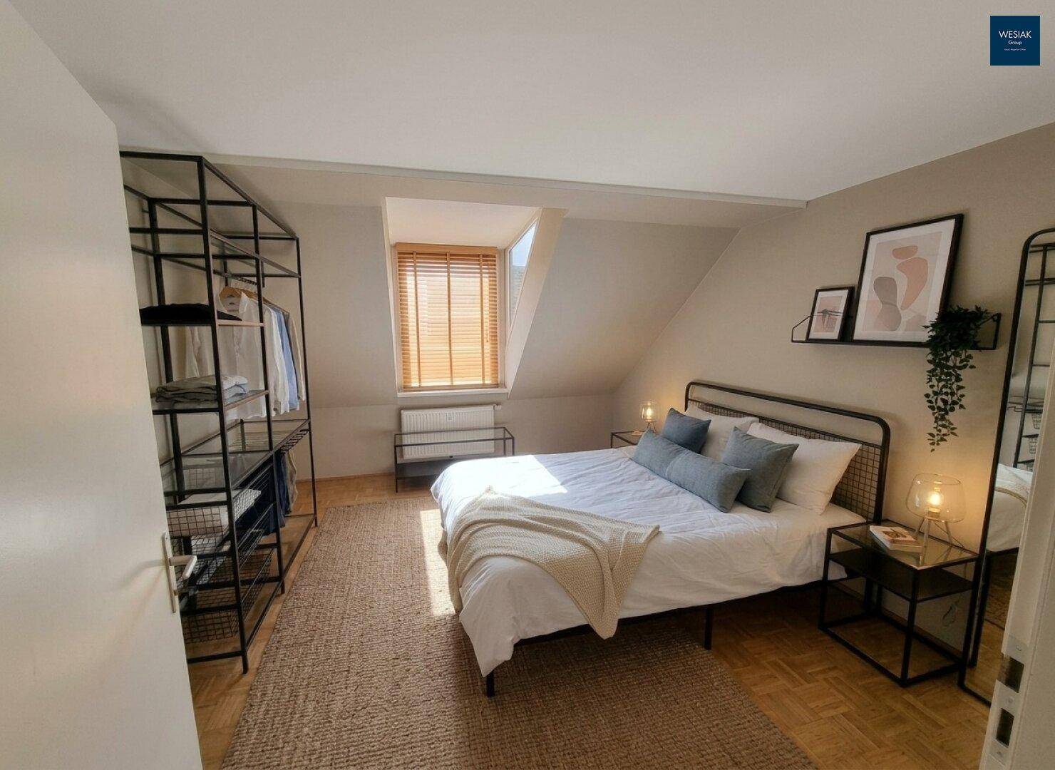Gemütliches Schlafzimmer im Dachgeschoss mit Doppelbett, offenem Kleiderschrank und Holzboden.