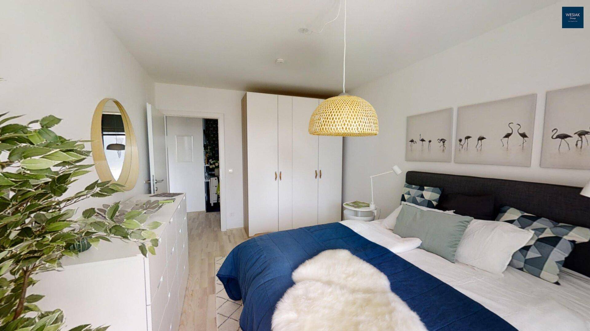 Helles Schlafzimmer mit Doppelbett, Einbauschränken und Zugang zu einem Balkon oder Terrasse.