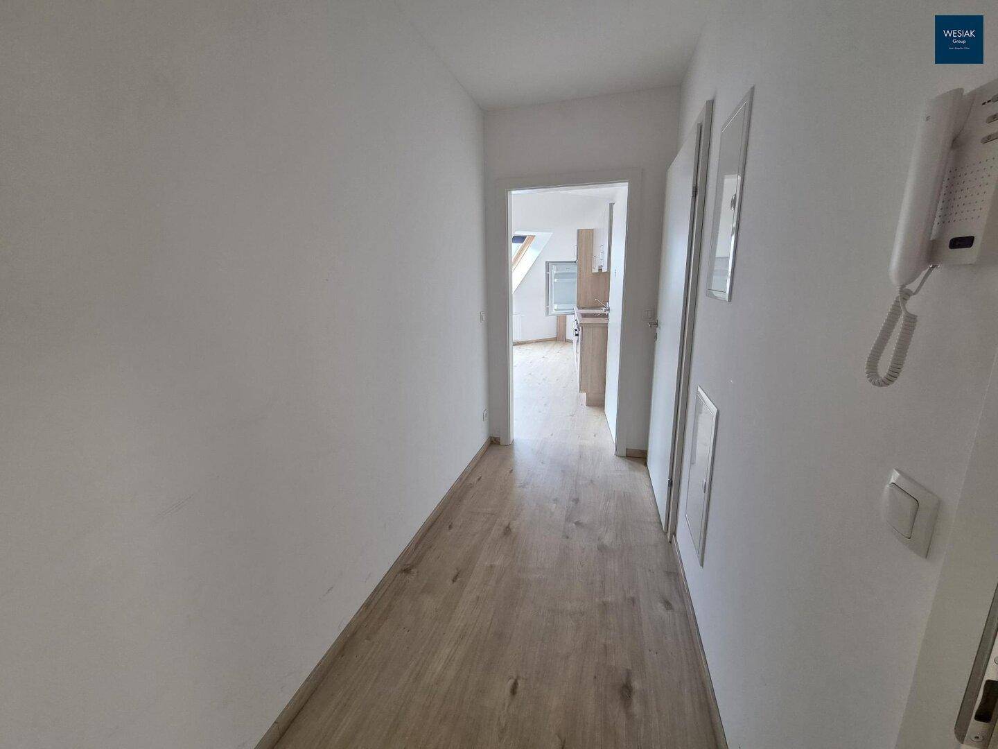 Heller Flur mit Laminatboden und Zugang zu weiteren Räumen im Dachgeschoss.