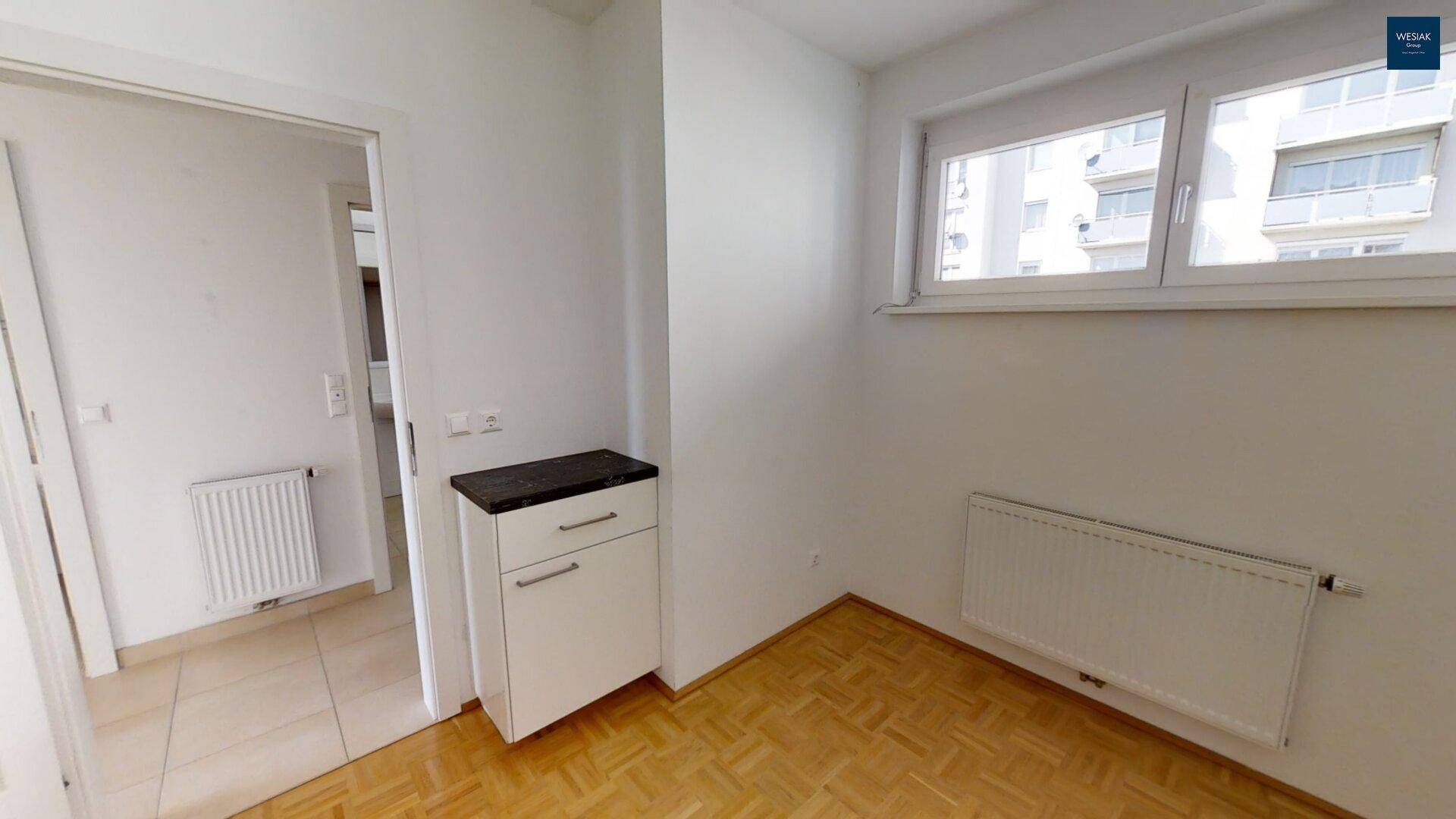 Kleiner Raum mit Parkettboden, Fenster und einem Unterschrank mit dunkler Platte.