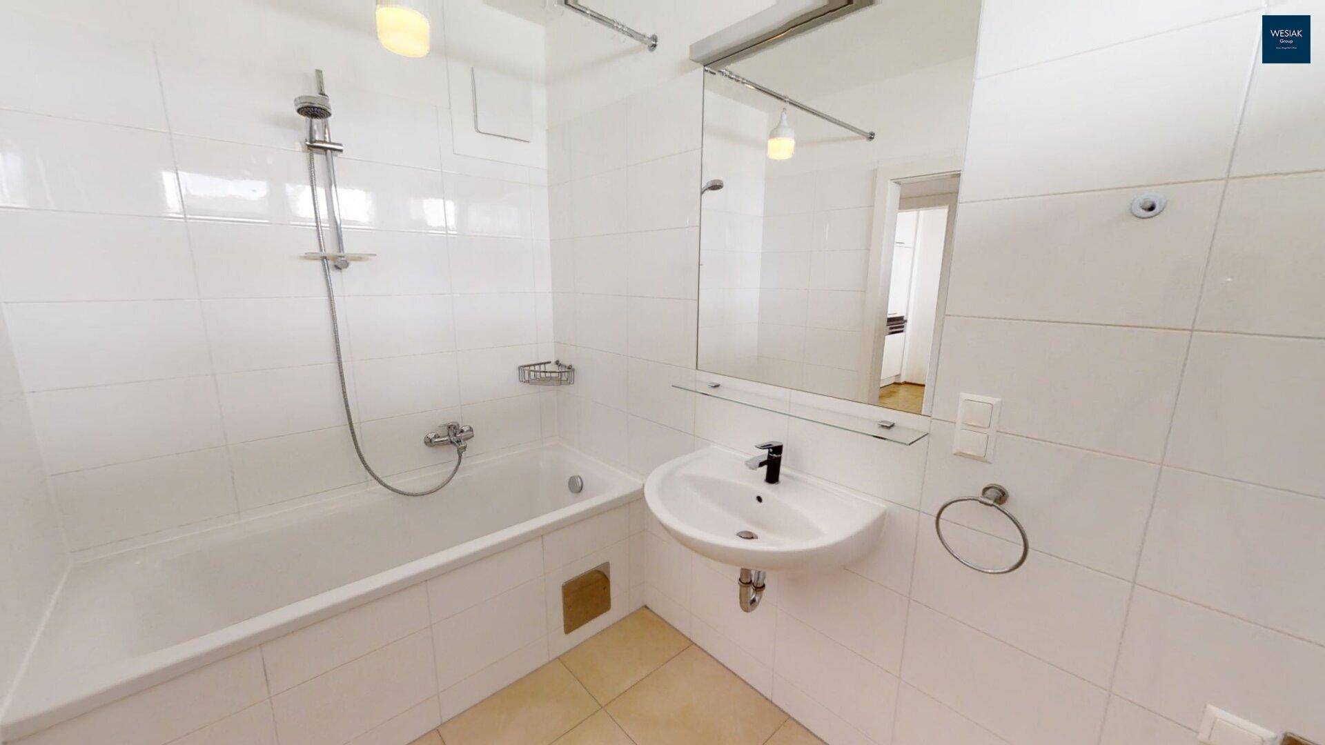 Badezimmer mit Badewanne, Duschfunktion, Waschbecken und großem Spiegel.