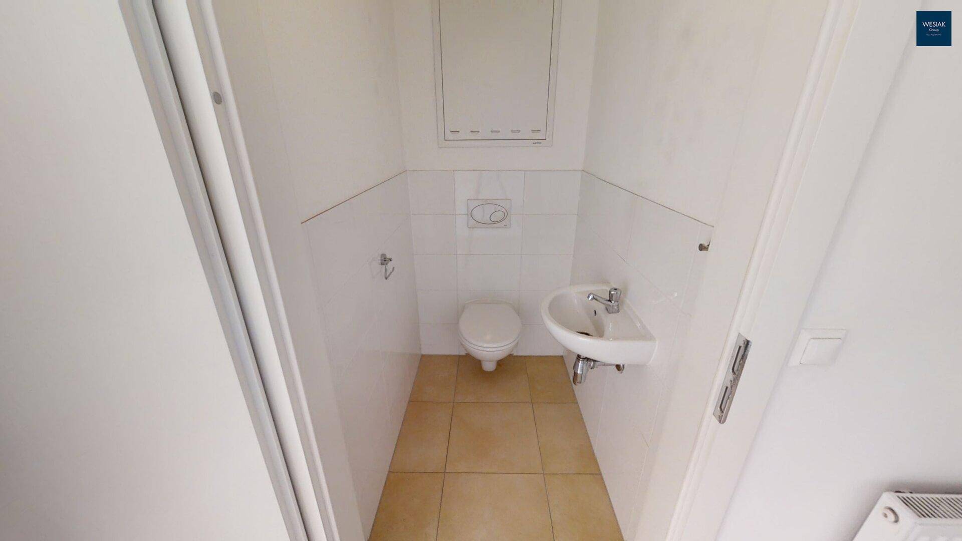 Funktionelles Gäste-WC mit Wand-WC und kleinem Handwaschbecken.