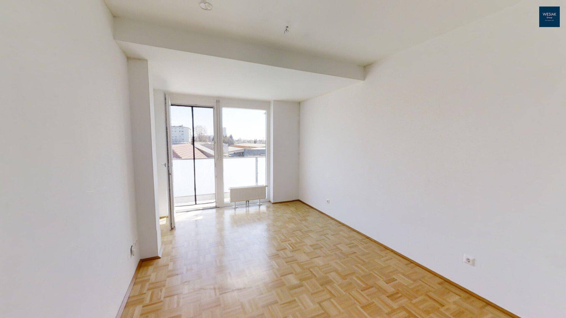 Lichtdurchflutetes Wohnzimmer mit Parkettboden und breiter Fensterfront zum Außenbereich.