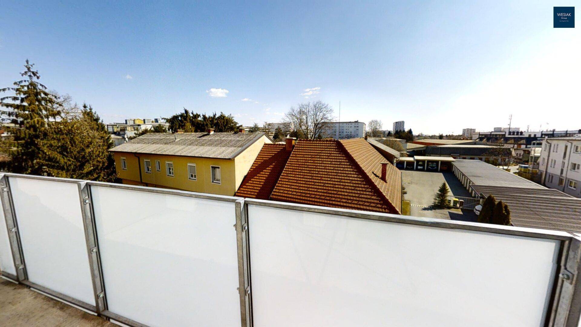 Weitblick über Dächer und umliegende Gebäude von einem Balkon aus.
