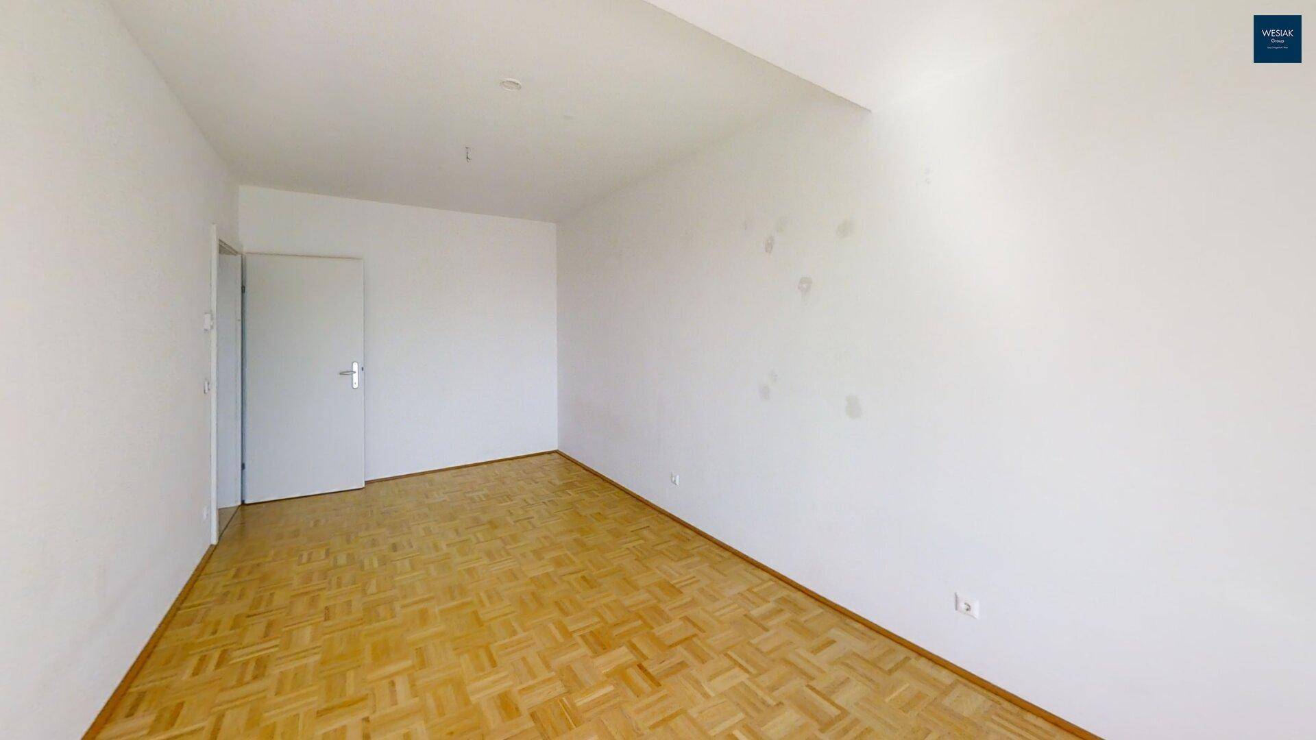 Helles Schlafzimmer mit Parkettboden und weißen Wänden, bereit zur Einrichtung.