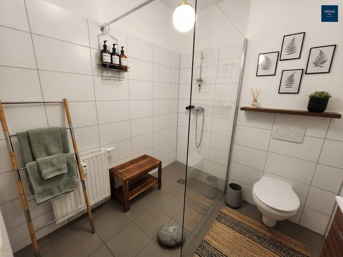 Modernes Badezimmer mit ebenerdiger Dusche, weißen Fliesen und Wand-WC.