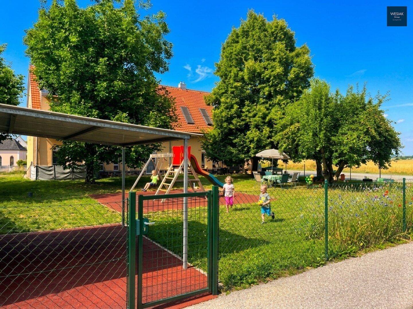 Großer Gartenbereich mit Kinderspielplatz, Rutsche und Schaukeln für Familien.
