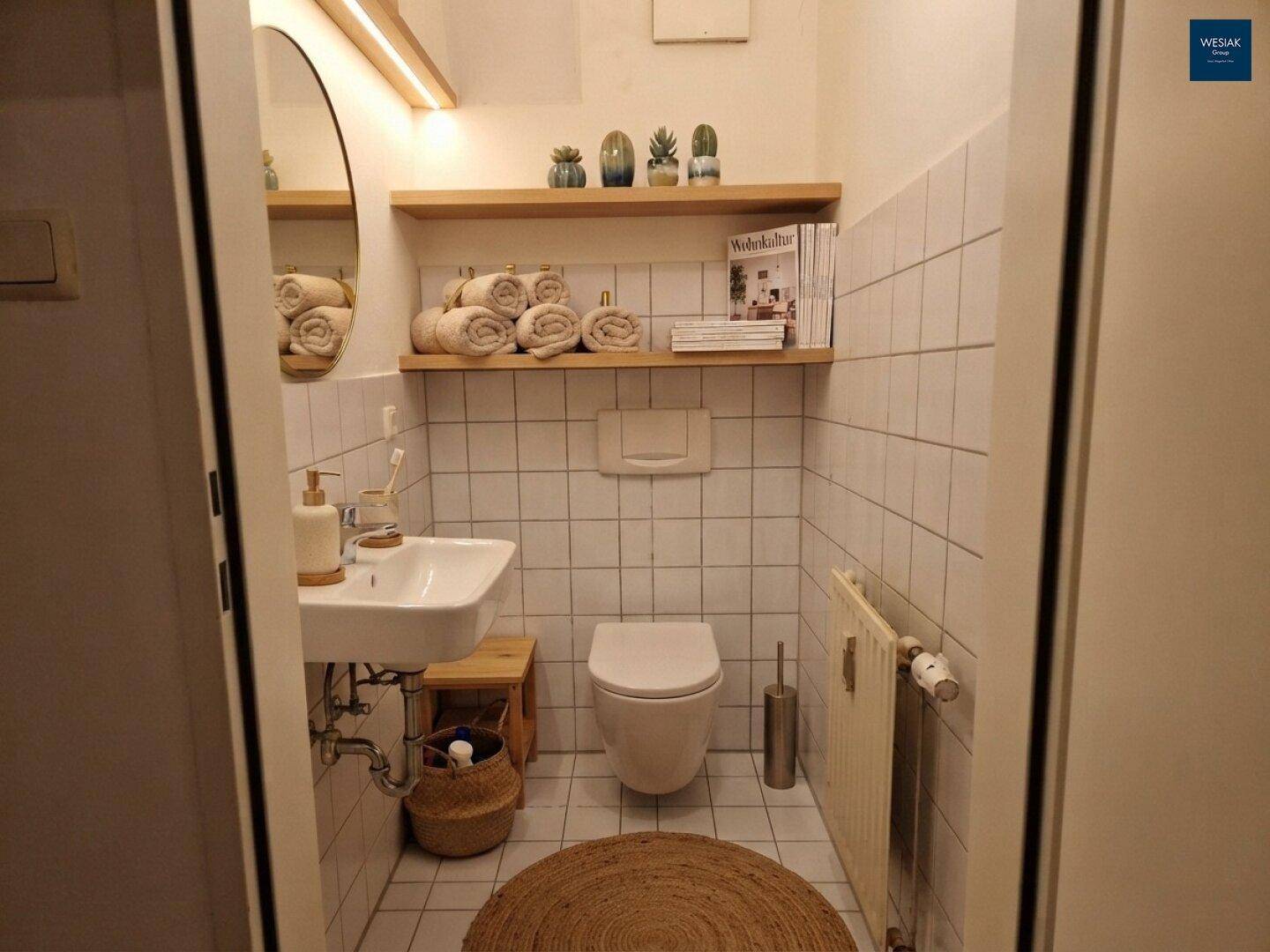 Kleines Gäste-WC mit Wand-WC, Waschbecken und weißen Fliesen.