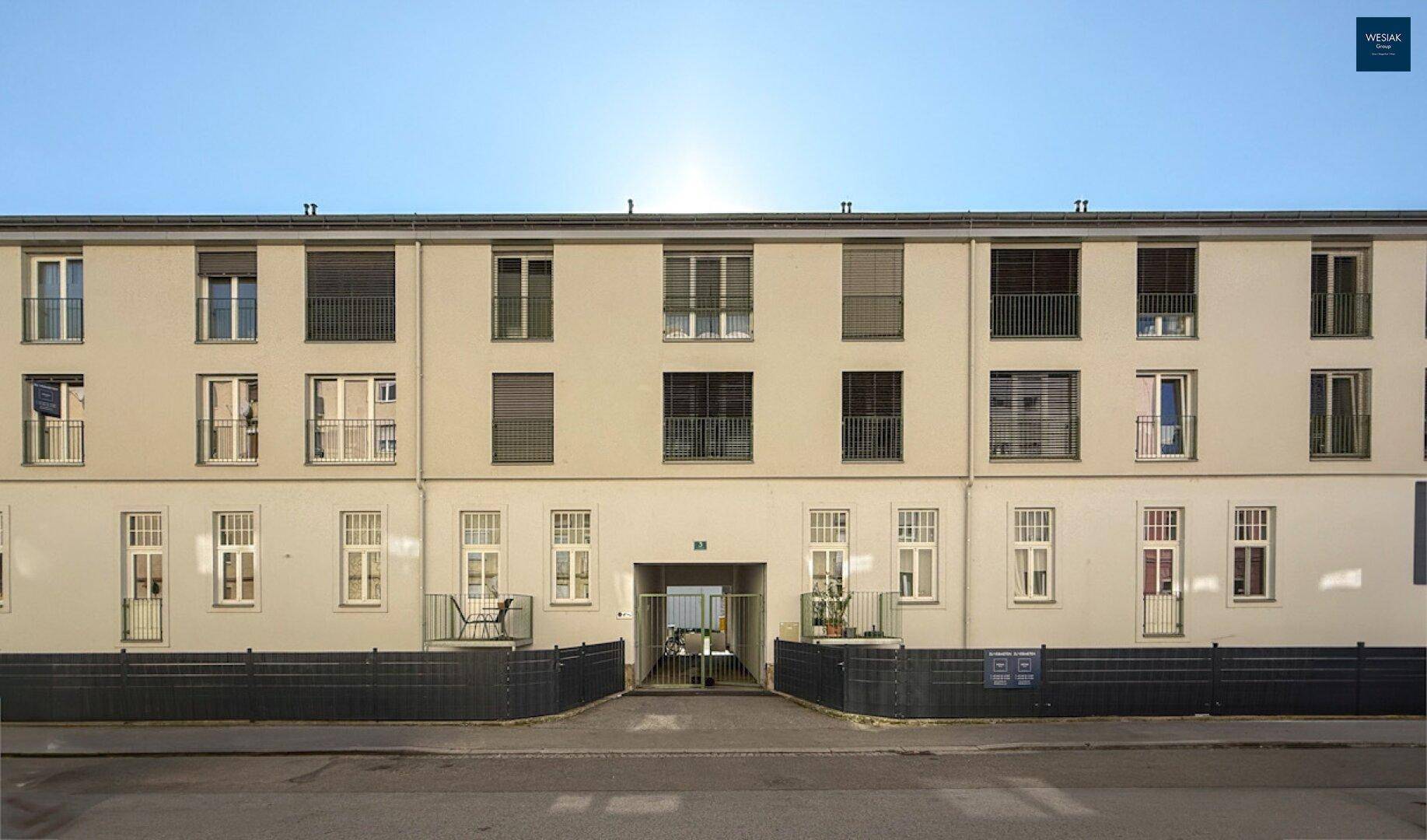 Fassade eines Wohngebäudes mit vielen Fenstern und französischen Balkonen, direkt an einer Straße gelegen.
