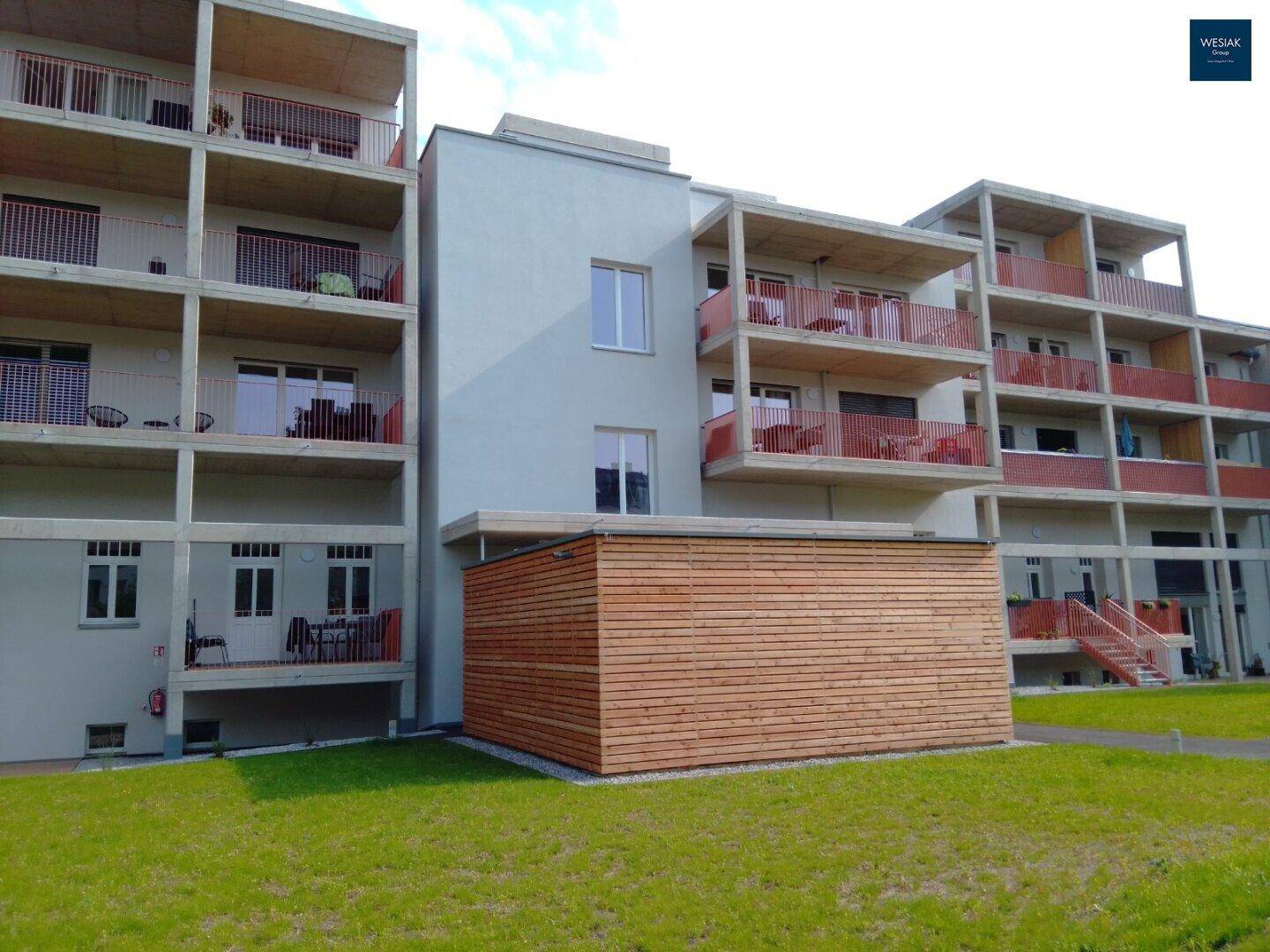 Ansicht eines modernen Wohnkomplexes mit mehreren Balkonen und einer Holzverkleidung im unteren Bereich.