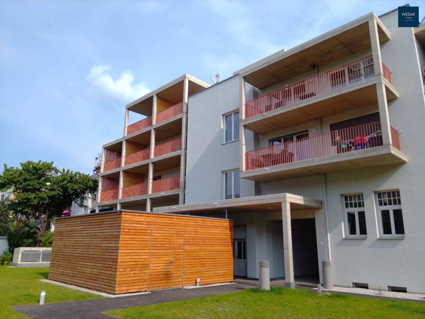 Schräge Ansicht des modernen Wohngebäudes mit Balkonen und einer Holzfassade im Erdgeschoss.