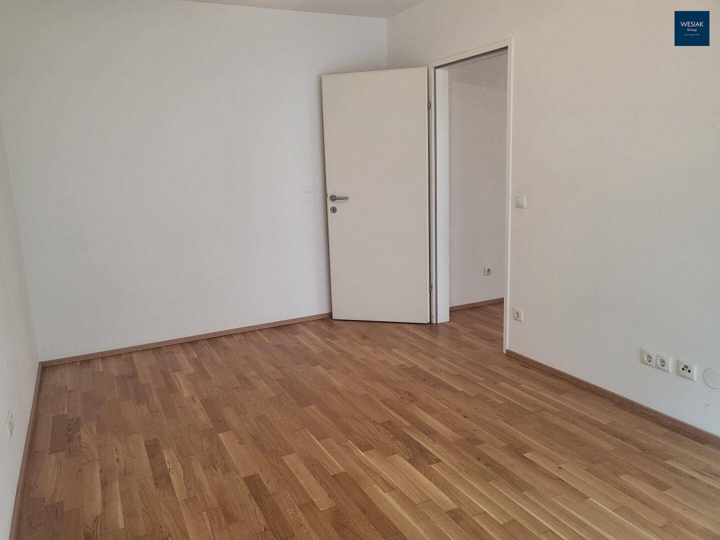 Heller Raum mit Parkettboden und weißen Wänden, bereit zur individuellen Gestaltung.