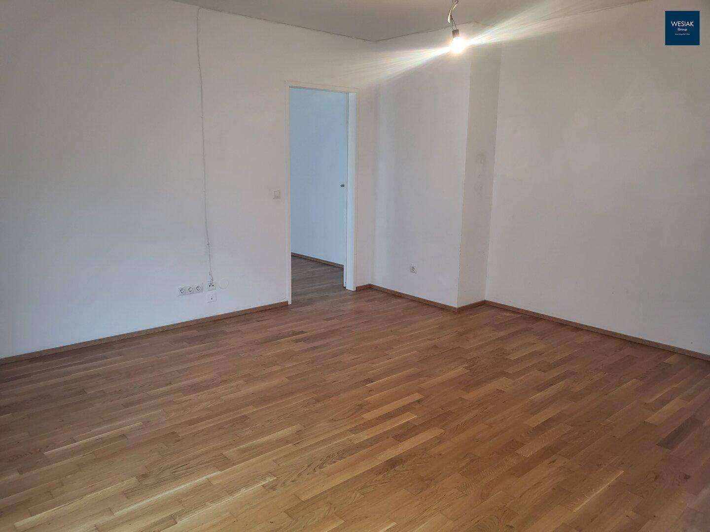 Leerer Raum mit hellem Parkettboden und weißen Wänden, bietet flexible Nutzungsmöglichkeiten.