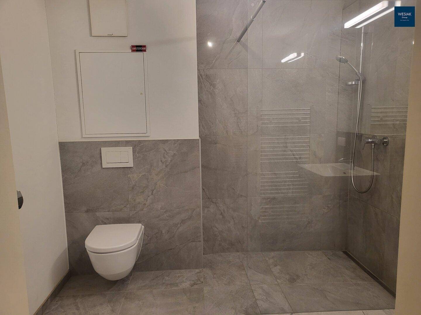 Modernes Badezimmer mit wandhängendem WC und geräumiger begehbarer Dusche.