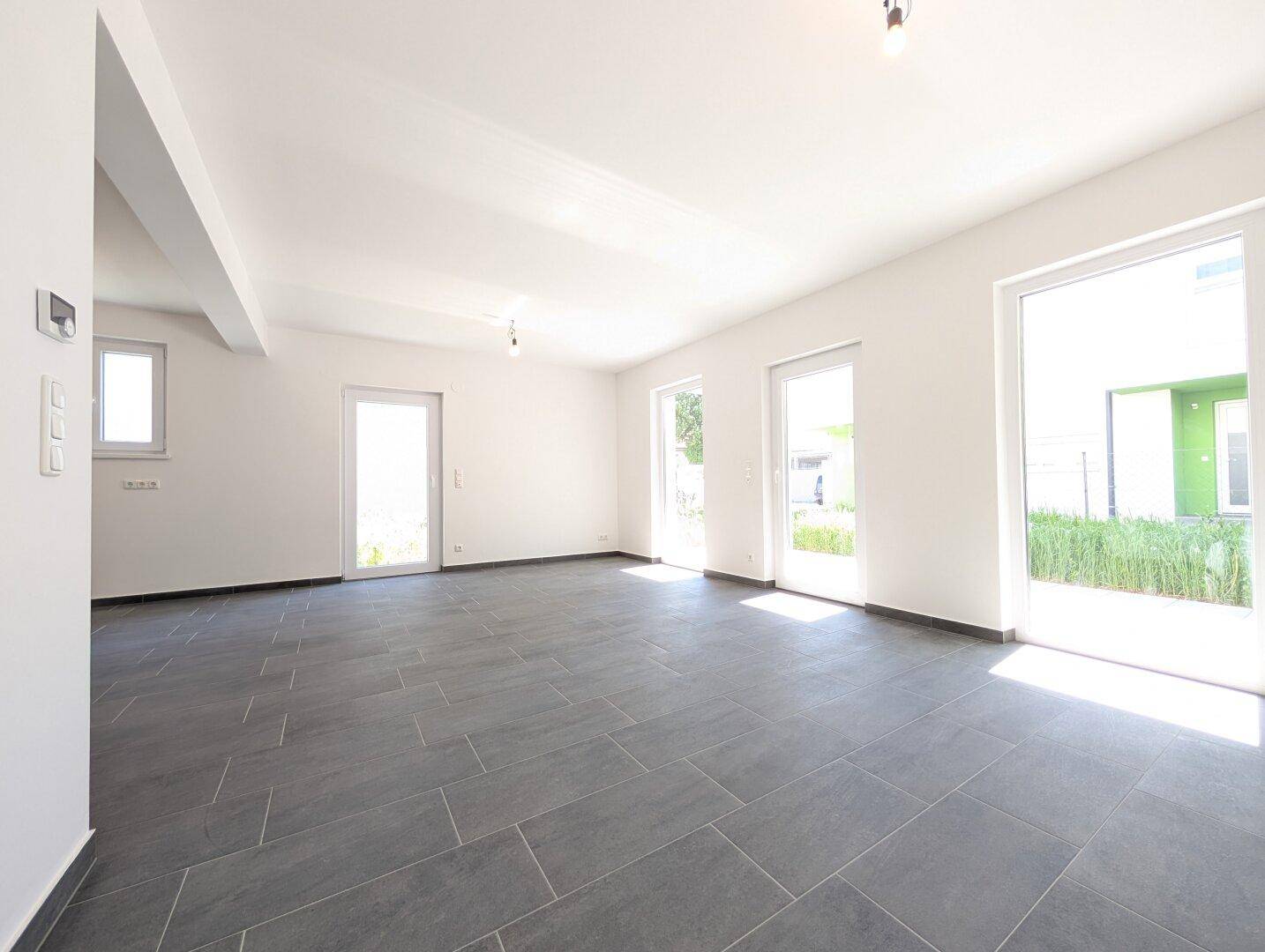 Großzügiger, heller Wohnbereich mit Fliesenboden und direktem Zugang zur Terrasse und Garten.