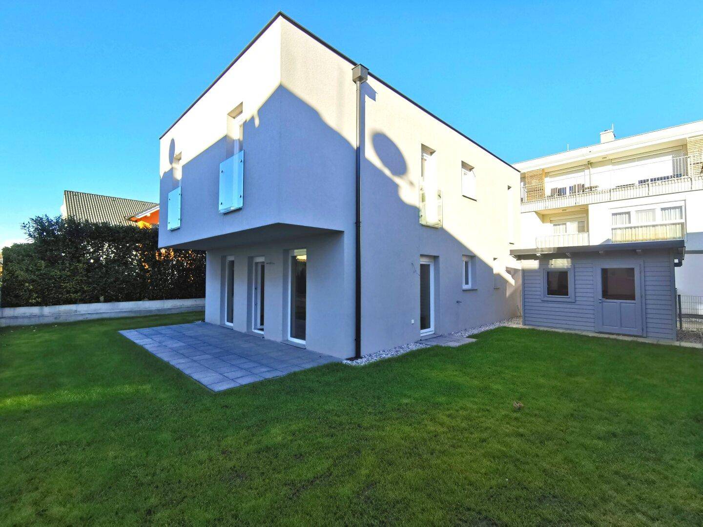 Modernes Einfamilienhaus mit gepflegtem Garten, Terrasse und schlichter Fassadengestaltung.