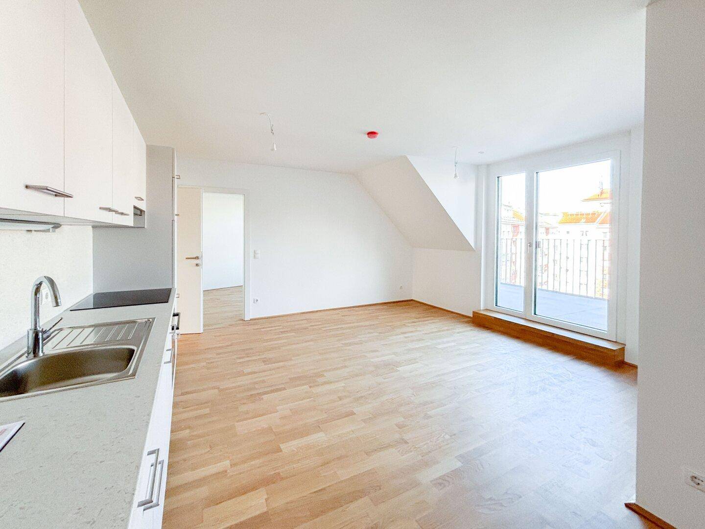 Heller offener Wohn-Essbereich mit integrierter Küche und Holzboden, ideal für modernes Wohnen.