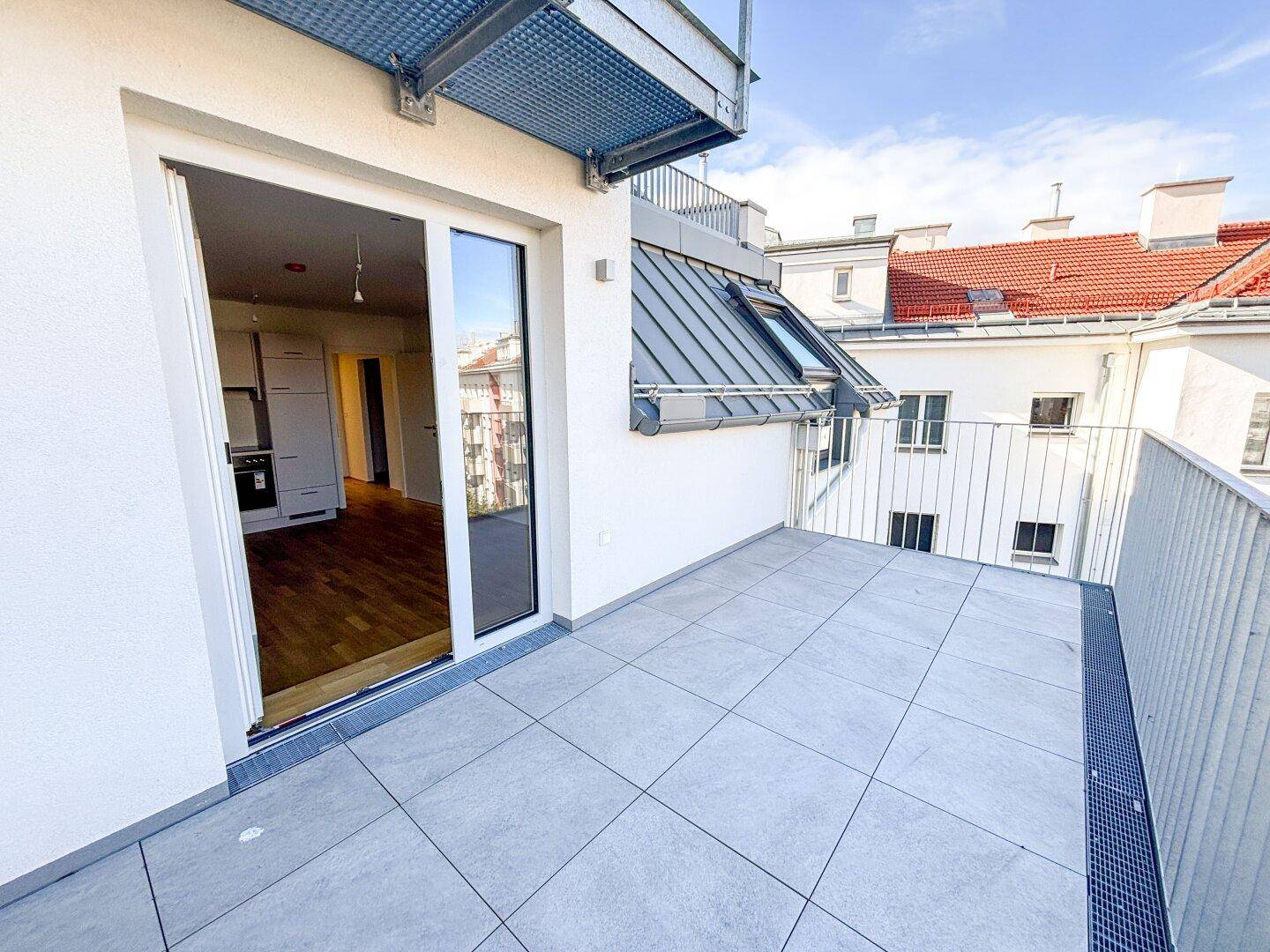 Moderner Balkon mit Fliesenboden und Blick auf die Umgebung, direkt zugänglich vom Wohnbereich.