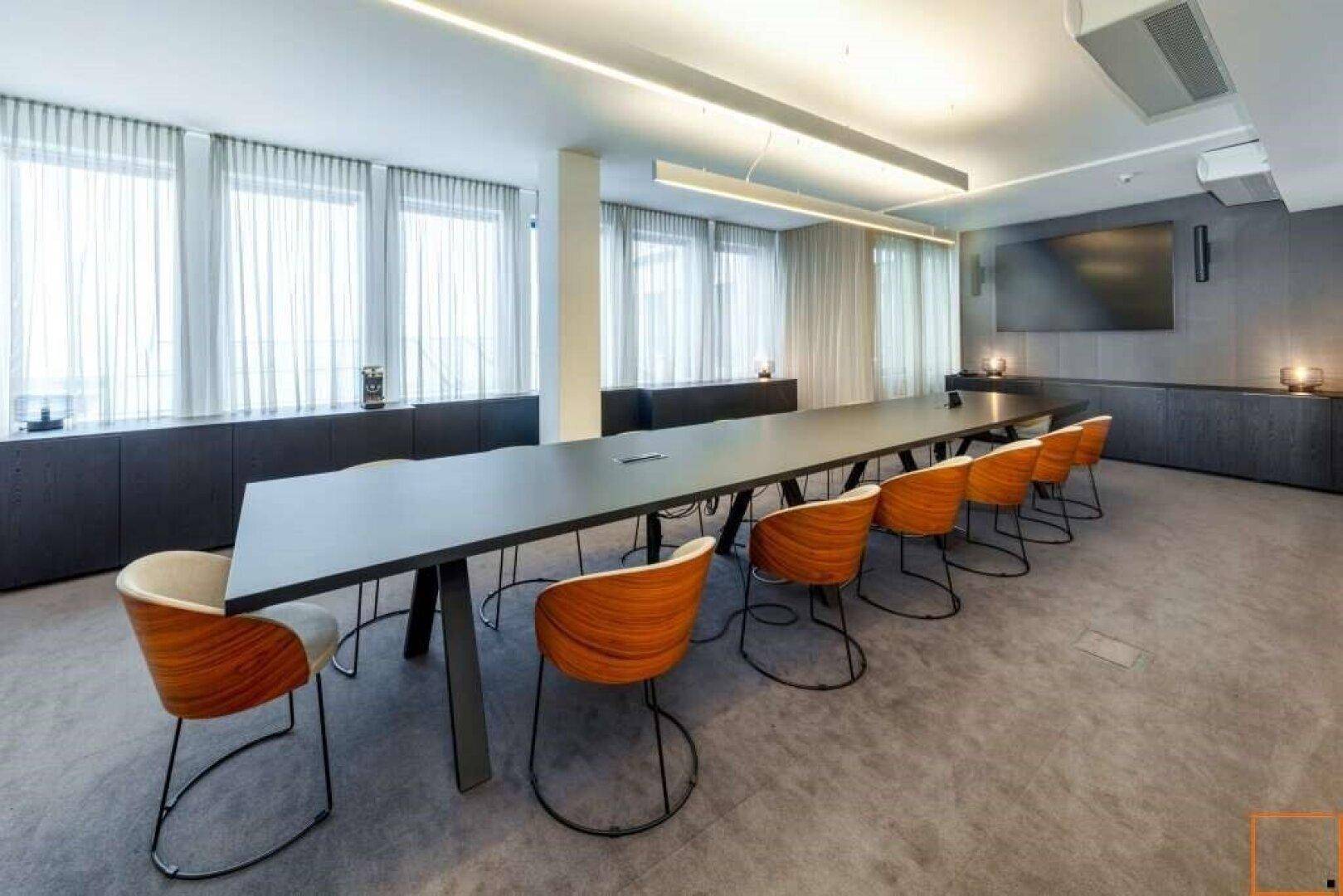Moderner Konferenzraum mit langem Tisch, stilvollen Stühlen und großen Fenstern mit Vorhängen für Privatsphäre.