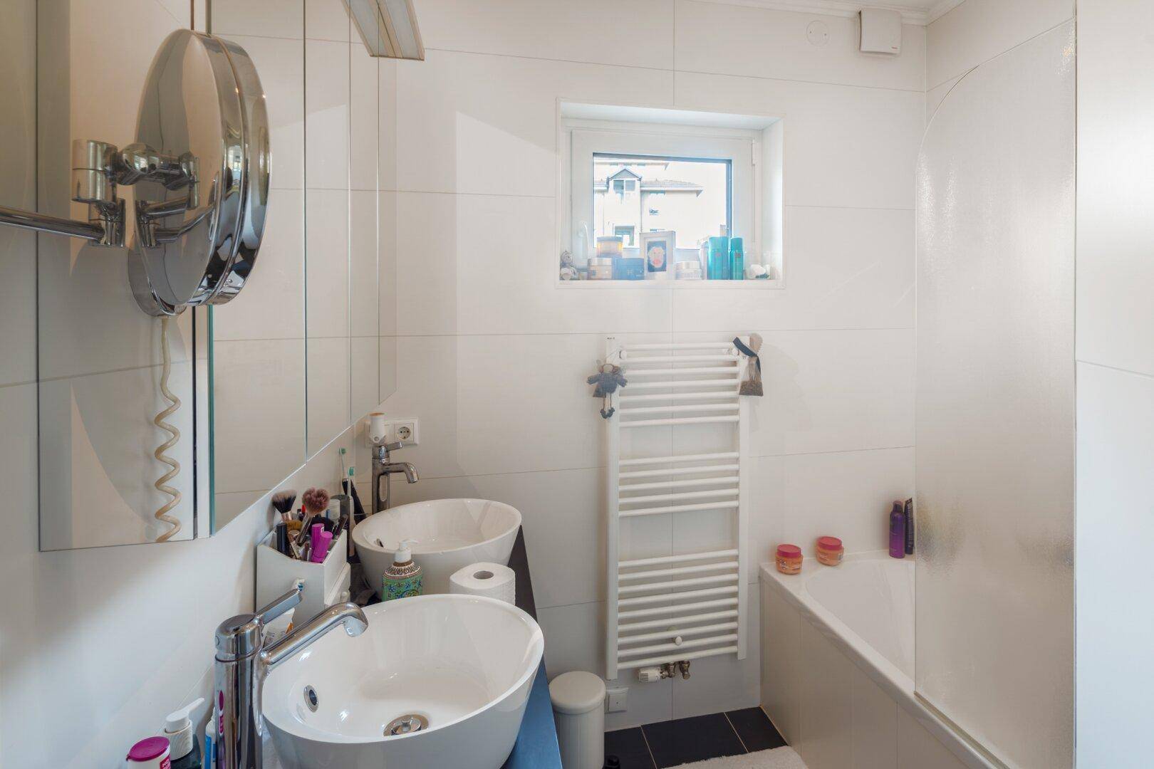 Modernes Badezimmer mit zwei Waschbecken, Badewanne und beheiztem Handtuchhalter.