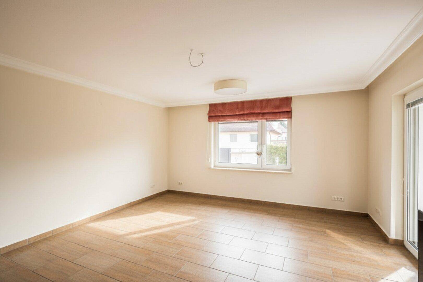 Helles, leeres Zimmer mit Fliesenboden und Zugang zur Terrasse.
