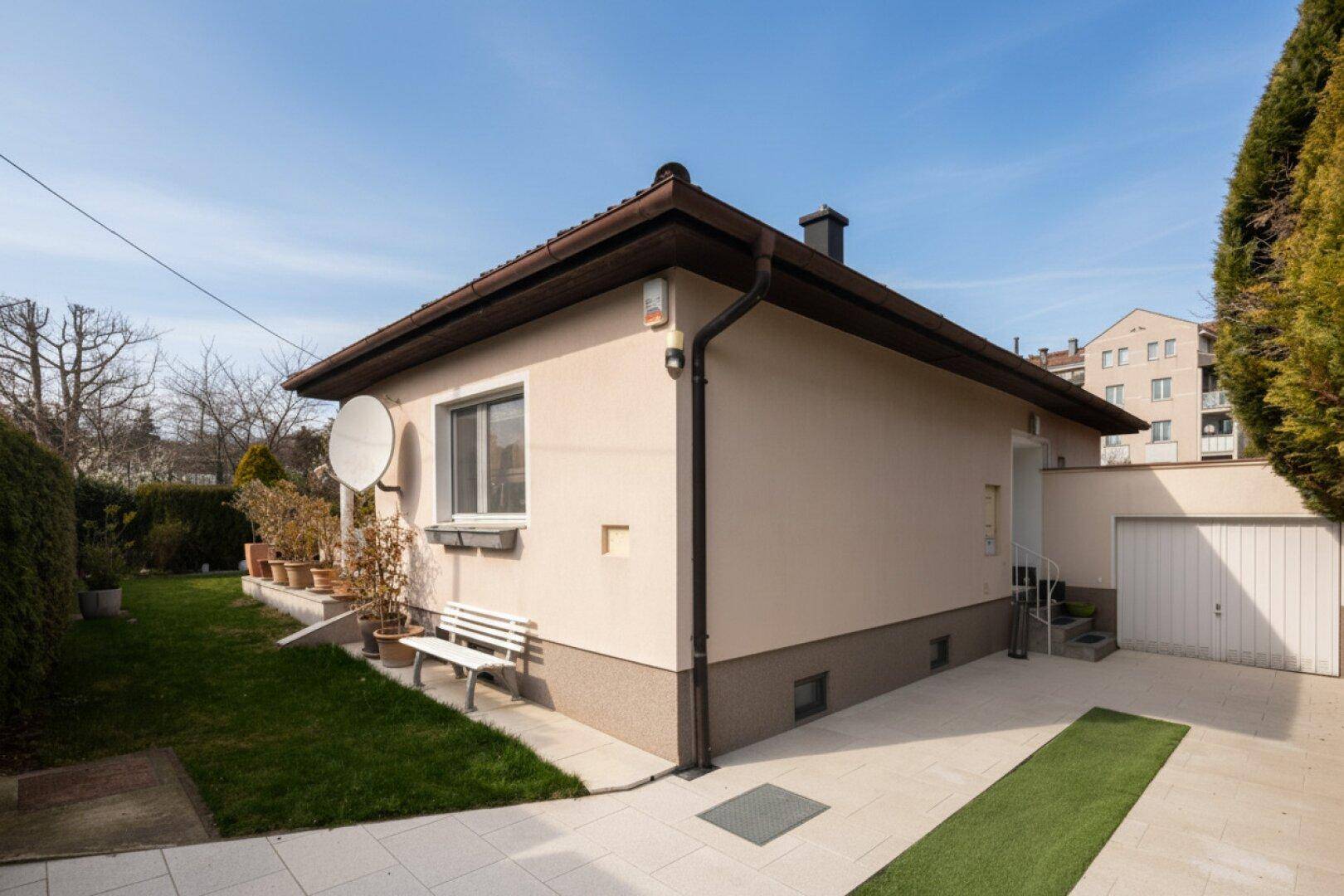 Seitenansicht des Einfamilienhauses mit Garage, Zufahrt und gepflegtem Vorgartenbereich.