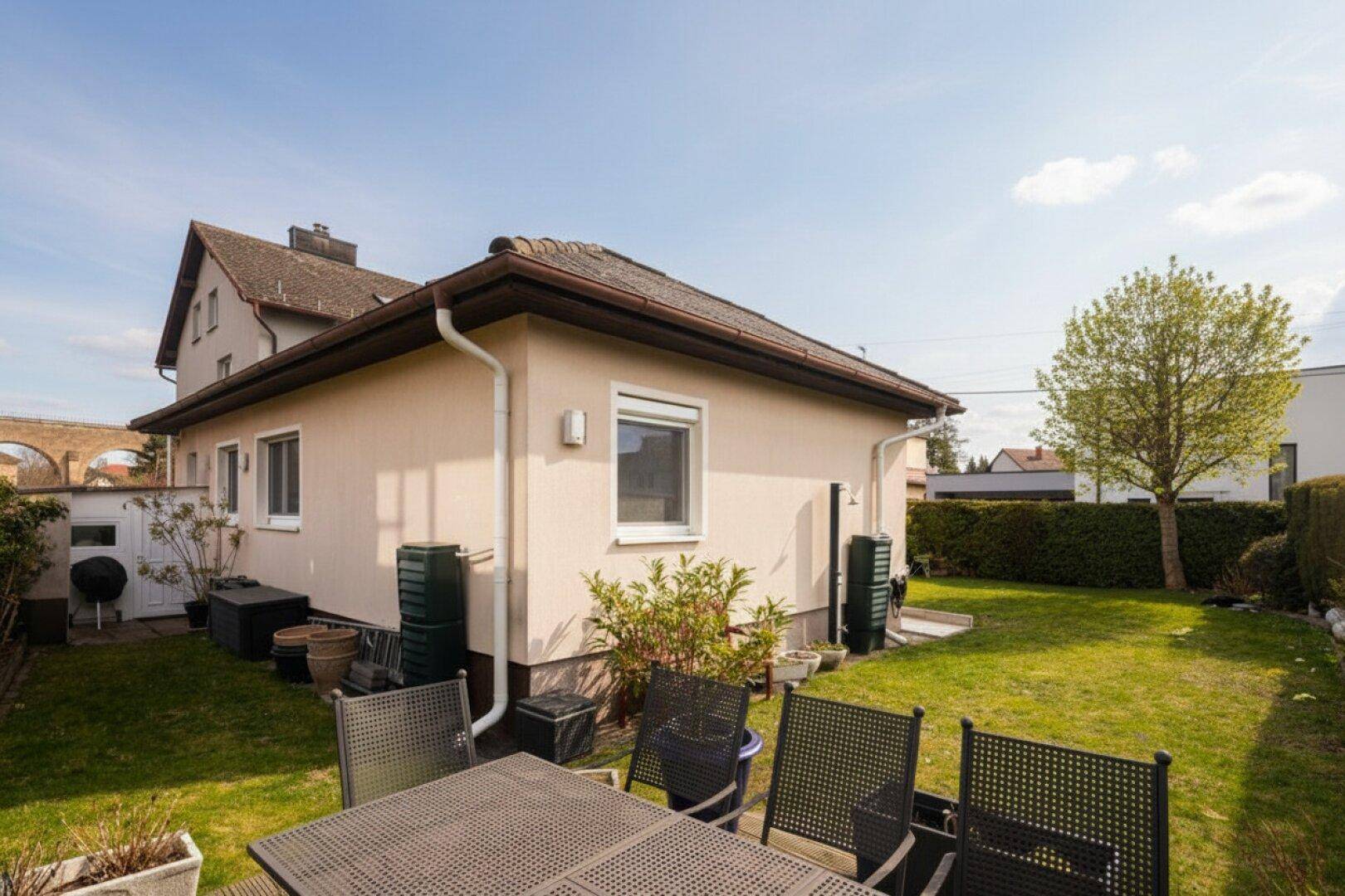 Rückansicht des Hauses mit großem Garten, Außensitzbereich und Blick auf die Umgebung.