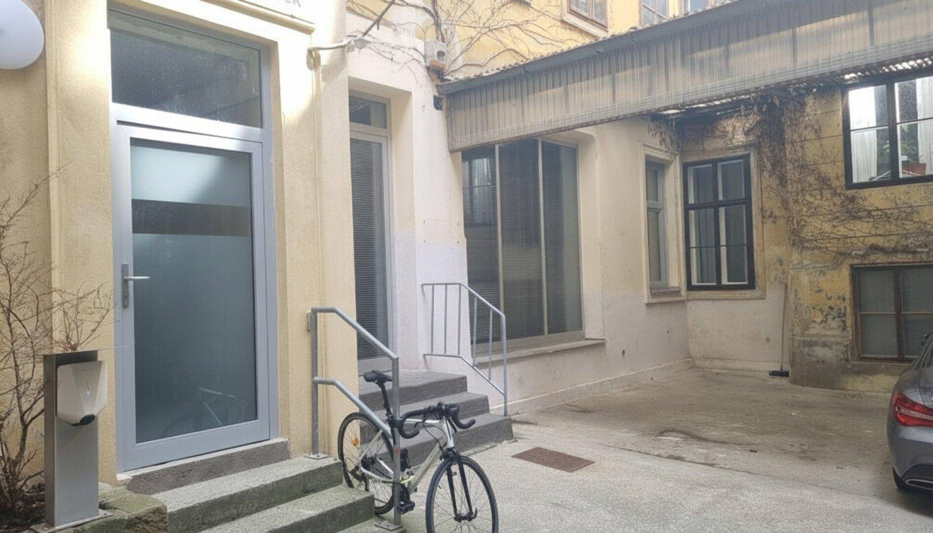 Eingangsbereich im Innenhof mit Fahrrad und Treppen zu den verschiedenen Türen.