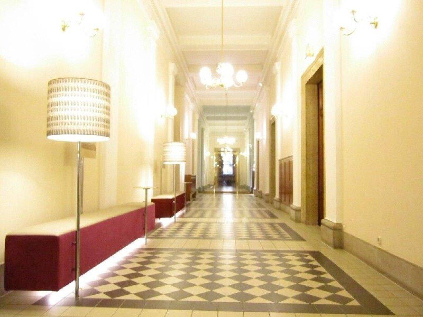 Langer, eleganter Flur mit Schachbrettmuster-Boden, hohen Decken und dekorativen Leuchten, die den Raum erhellen.
