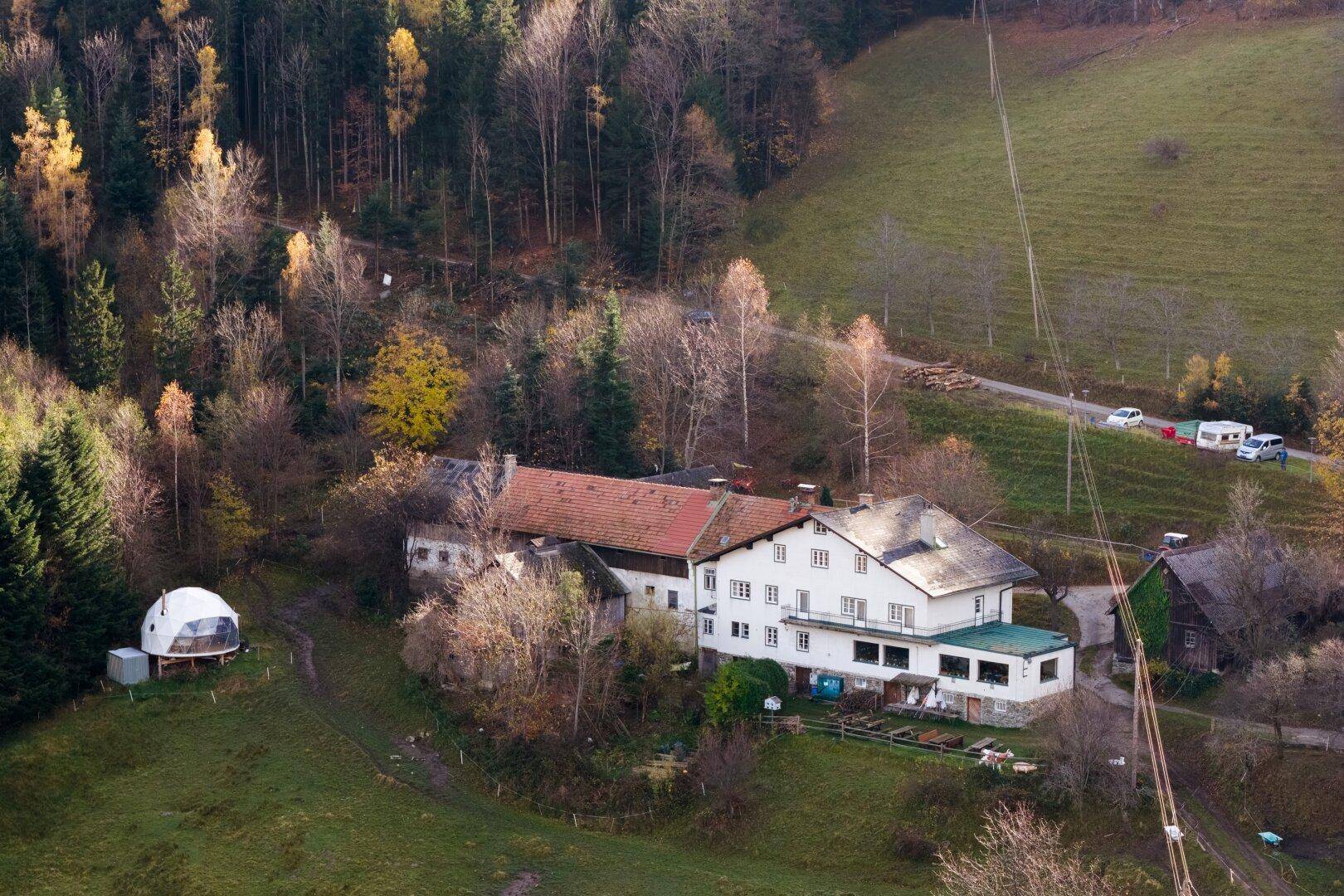 Luftaufnahme des Anwesens in einer bewaldeten Hügellandschaft mit Zufahrtsstraße.