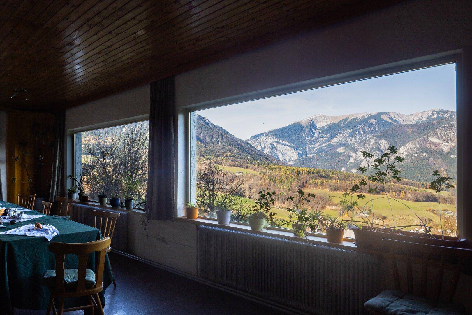 Heller Speisesaal mit Panoramafenstern, die einen weiten Blick auf die Berglandschaft bieten.