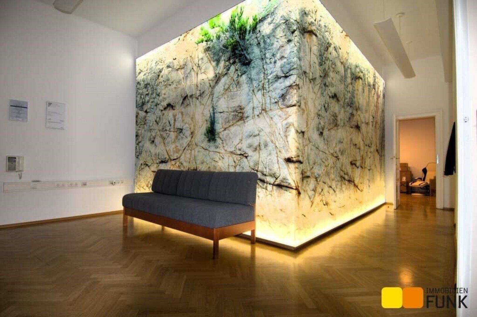 Empfangsbereich mit einer beeindruckenden, hinterleuchteten Wandinstallation und bequemer Sitzbank.