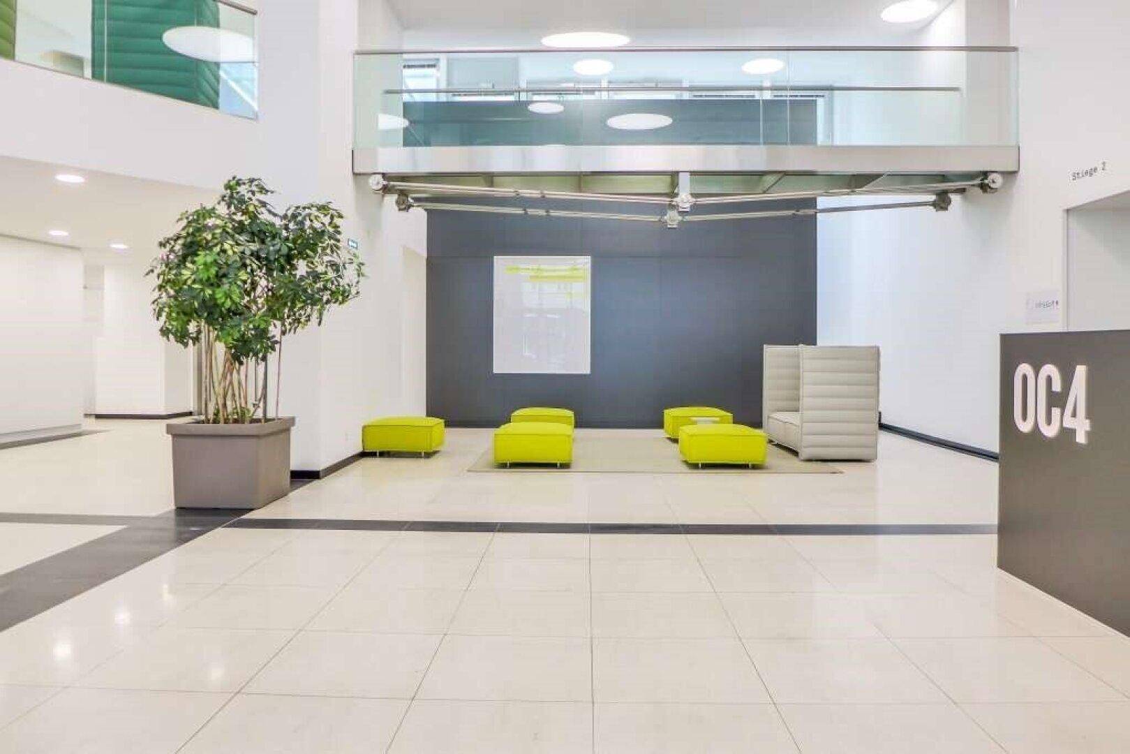 Helle und moderne Lobby eines Bürogebäudes mit Sitzgelegenheiten, Fliesenboden und Galerie.