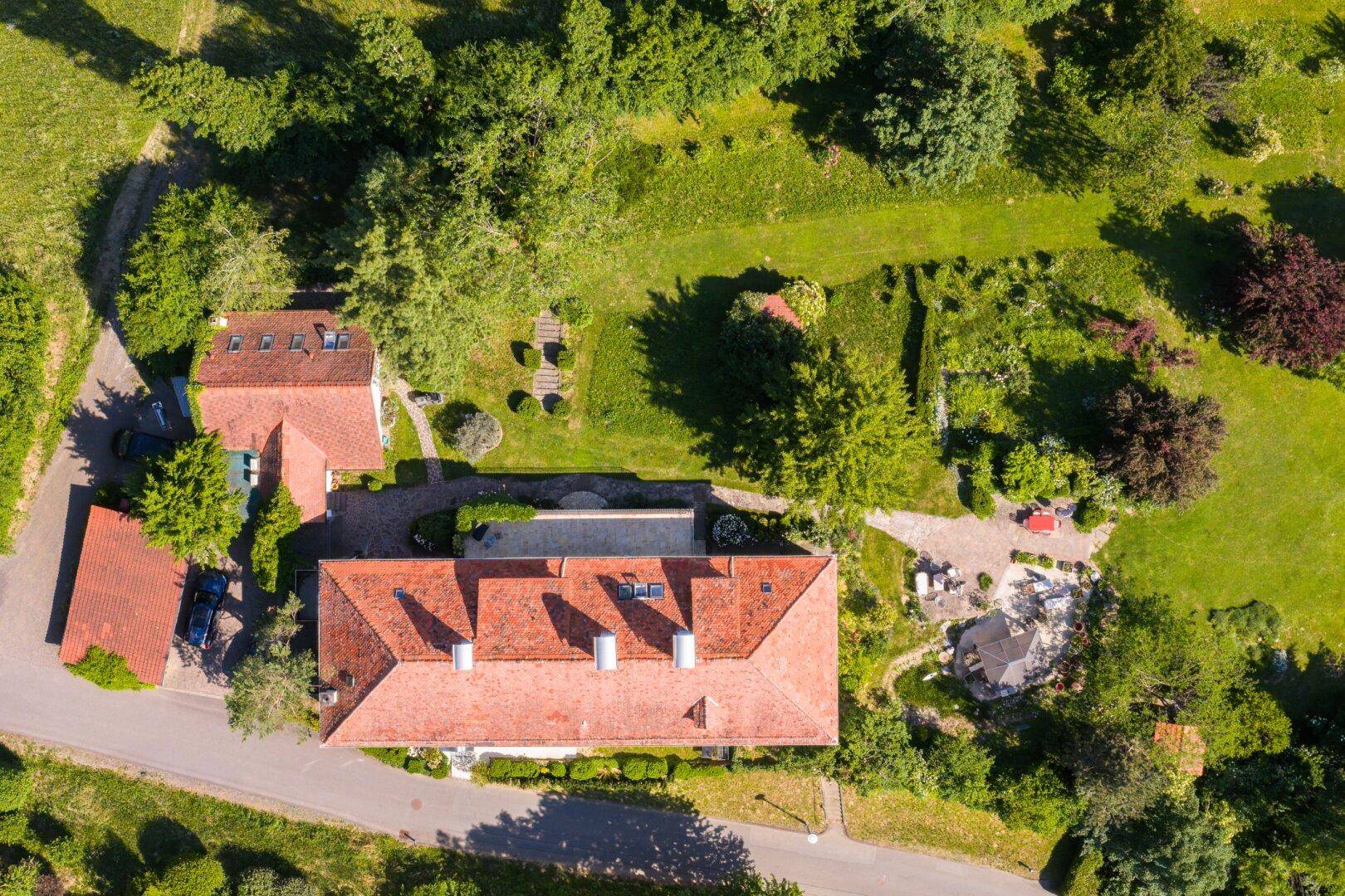 Luftaufnahme des Anwesens mit Hauptgebäude, Nebengebäuden und weitläufigen Grünflächen.