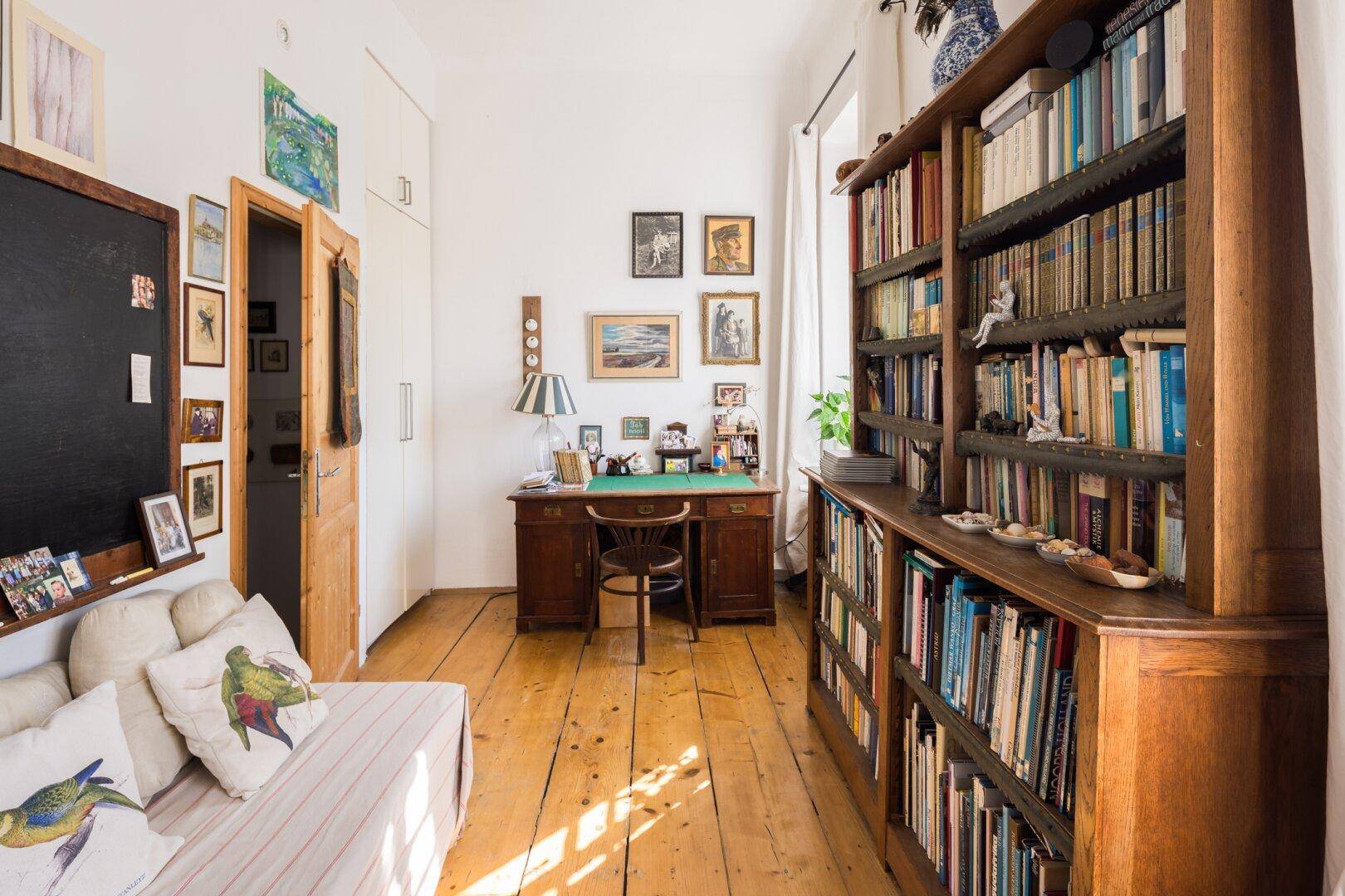 Arbeitszimmer mit großem Bücherregal, Schreibtisch und Holzboden, ideal für konzentriertes Arbeiten.