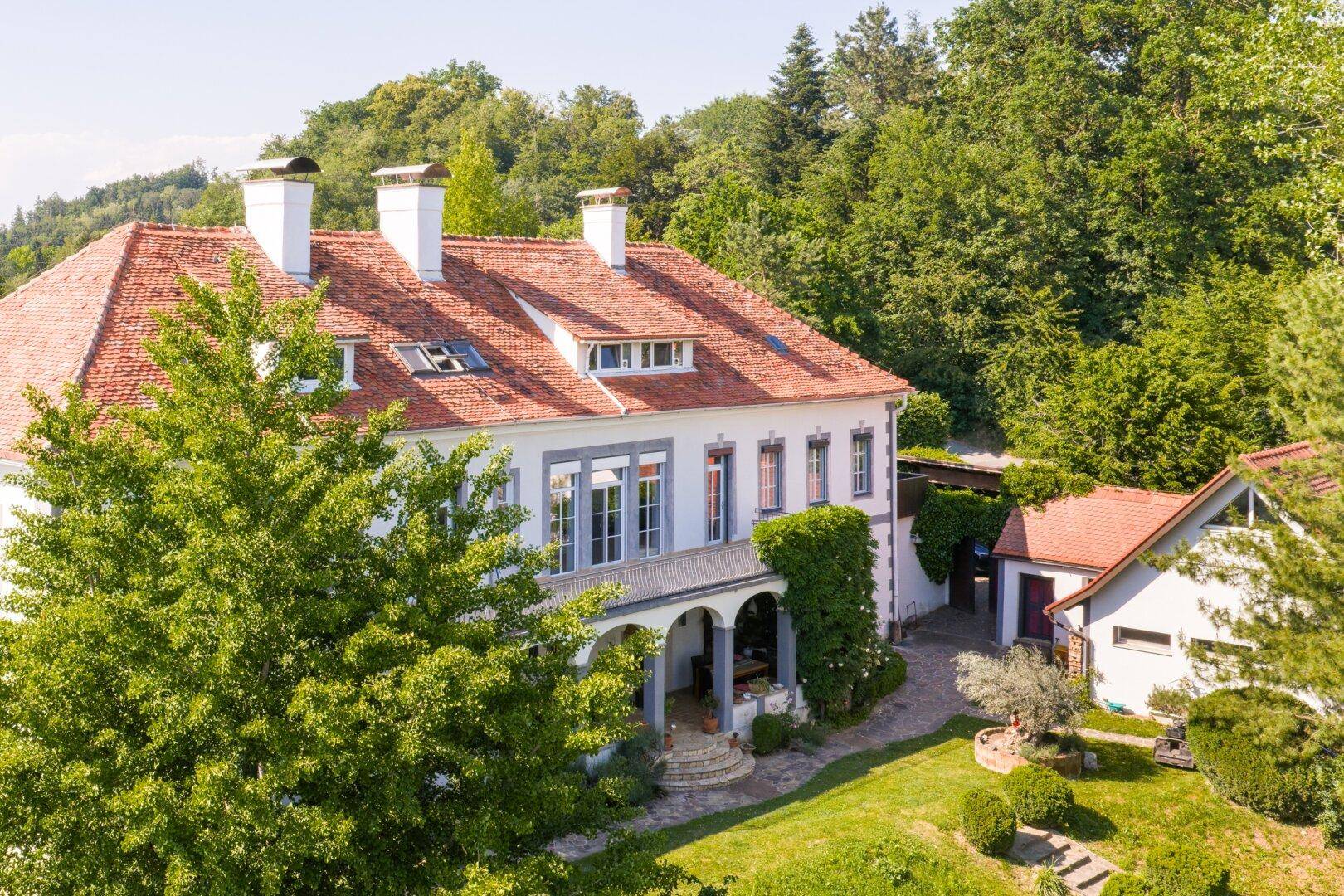 Ansicht der Villa mit überdachtem Eingangsbereich und üppiger Begrünung an der Fassade.